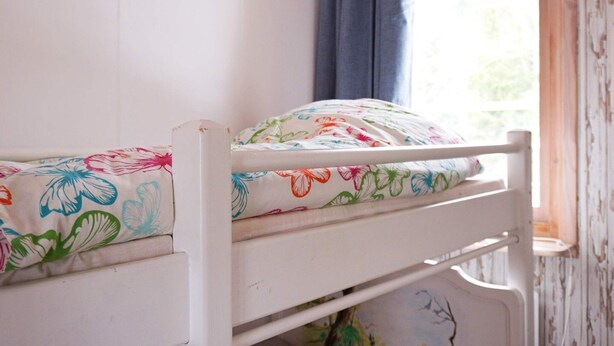 A bunk bed with floral bedding and a window with a view of greenery. - 3 Person Holiday Home in Munkedal (Munkedal)