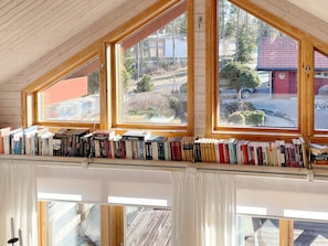 A room with a sloped ceiling, wooden beams, and a bookshelf filled with books. - 4 Person Holiday Home in Hammaro (Hammaro)