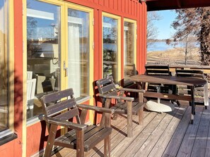 Una terraza de madera con mobiliario exterior y vista a un lago.