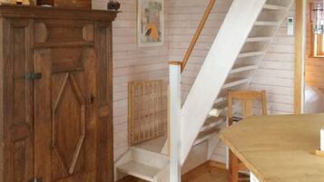Una habitación con un armario de madera, un cuadro, una escalera y una mesa.