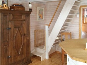 A room with a wooden cabinet, a painting, a staircase, and a table.