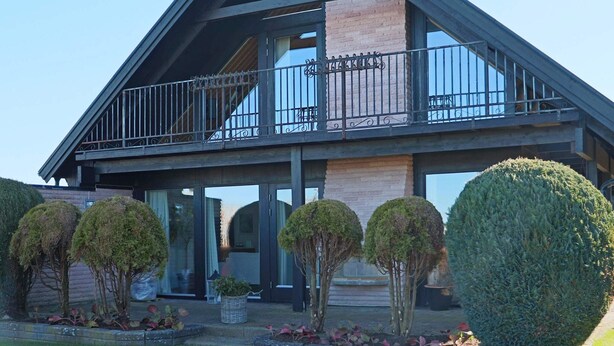 A modern house with a large balcony, a brick chimney, and neatly trimmed hedges. - 5 Star Holiday Home in Forslov (Förslöv)