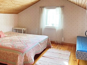A bedroom with a bed, a small table, a window with curtains, and a radiator. - 5 Person Holiday Home in Bodafors (Bodafors)