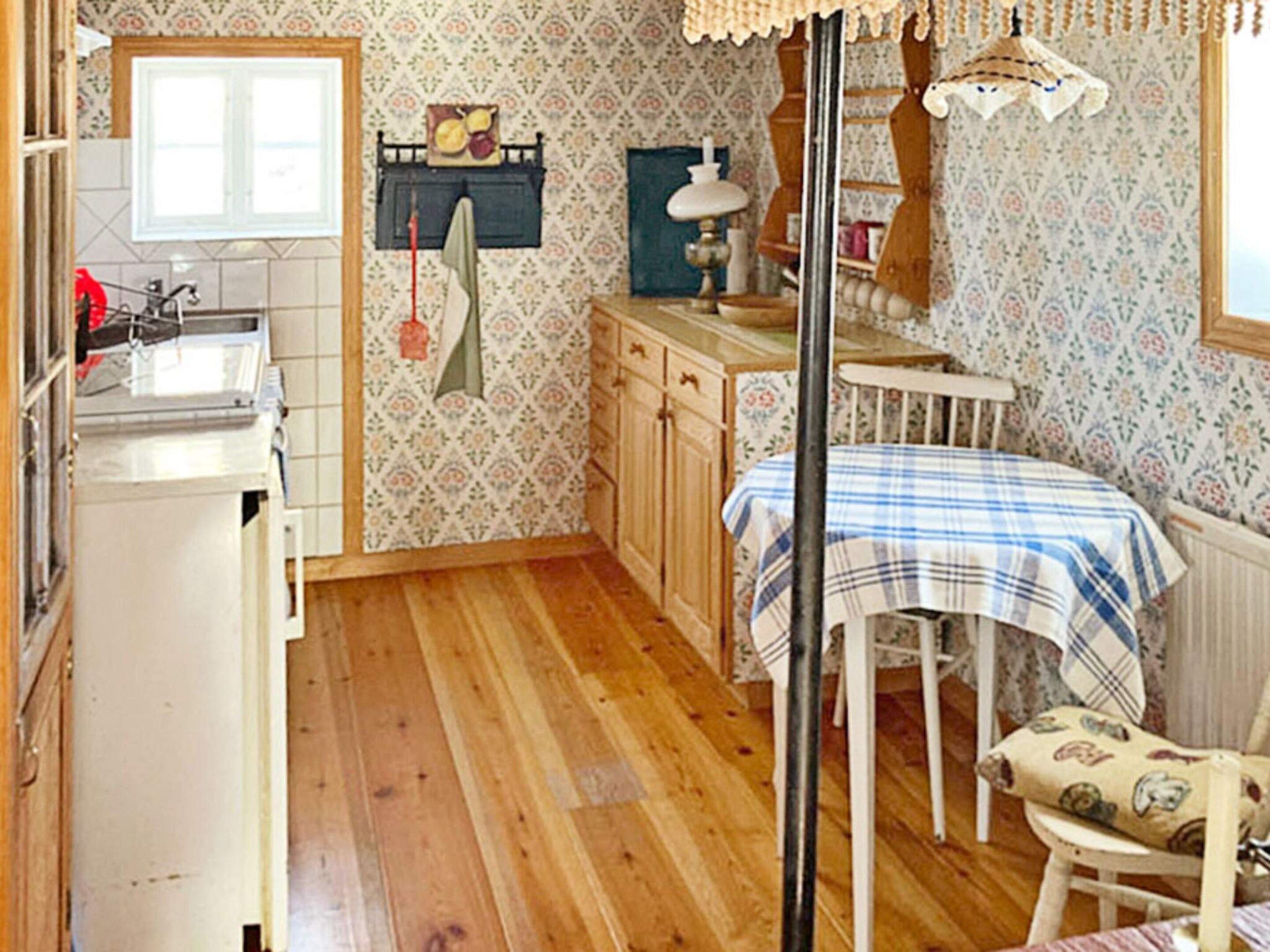 A compact kitchen with wooden cabinets, a sink, and a dining area with a table and chairs.