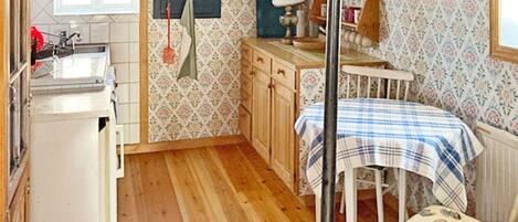 A compact kitchen with wooden cabinets, a sink, and a dining area with a table and chairs.