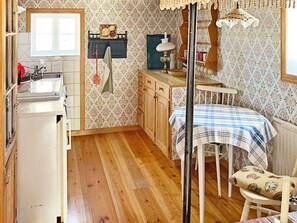 Une cuisine compacte avec des meubles de rangement en bois, un évier et un coin repas comprenant une table et des chaises.