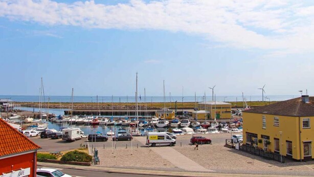 A marina with boats, a café, and a yellow building. - 4 Person Holiday Home in Nexo (Nexø)