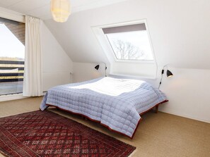 A bedroom with a sloped ceiling, a skylight, a bed with a patterned bedspread, two bedside lamps, and a red patterned rug. - 10 Person Holiday Home in Assens (Assens)