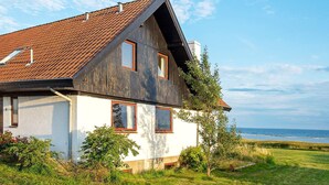 A two-story house with a sloped roof, a visible chimney, and a view of the sea. - 10 Person Holiday Home in Assens (Assens)