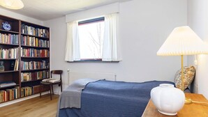 A bedroom with a bed, a bookshelf, a chair, a window, and a lamp. - 10 Person Holiday Home in Assens (Assens)