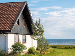 Et hus med skråt tag, hvide facader og havudsigt.