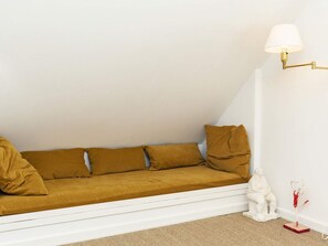 En hvid sofa med sennepsfarvede puder i et hjørne, en hvid væg og en hvid gulv.