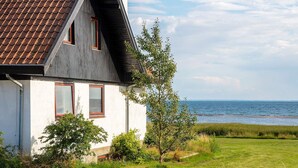 A house with a sloped roof, white exterior walls, and a view of the sea. - 10 Person Holiday Home in Assens (Assens)