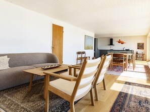 A modern living space with a sofa, dining table, chairs, and a kitchen area. - 10 Person Holiday Home in Assens (Assens)