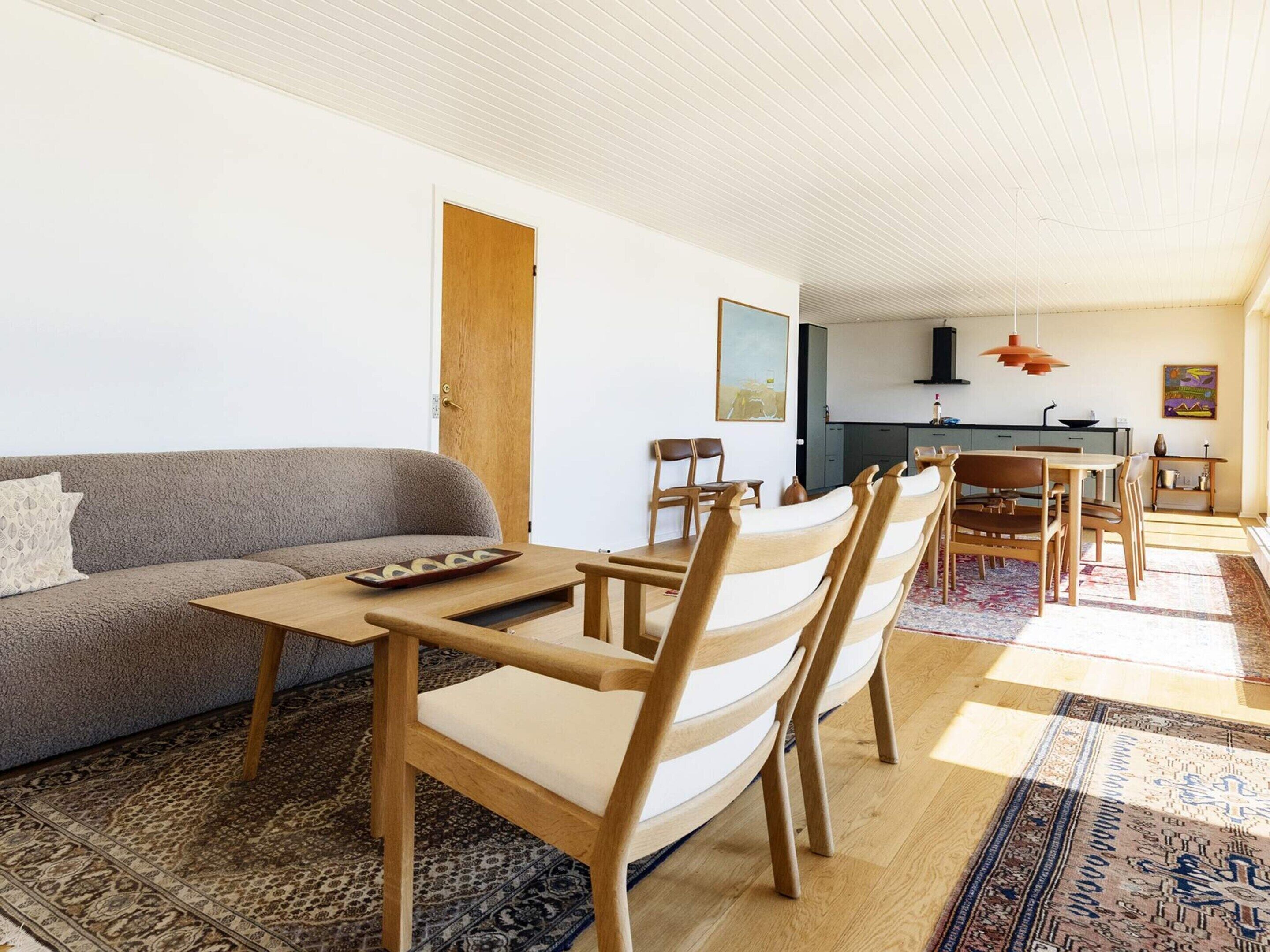 A modern living space with a sofa, dining table, chairs, and a kitchen area.