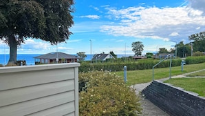 A patio area with a table and chairs, a view of the sea, and a pathway leading to a building. - Seaside Bliss in Sandkas - By Traum Ferienwohnungen (Allinge)