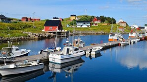 A harbor with boats docked, a red house, and a blue house. - 7 Person Holiday Home in Sortland (Sortland)