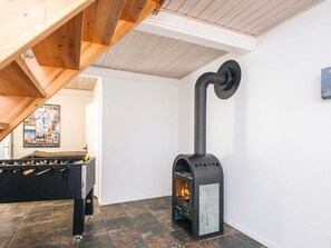 A room with a black wood-burning stove, a foosball table, and a tiled floor. - 16 Person Holiday Home in Haderslev (Haderslev)