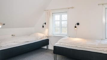 Quarto com duas camas, janela e radiador.
