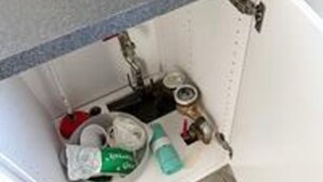 Een badkamer met een wastafel, toilet en opbergkast.