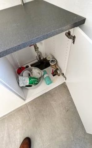 A bathroom with a sink, toilet, and storage cabinet.