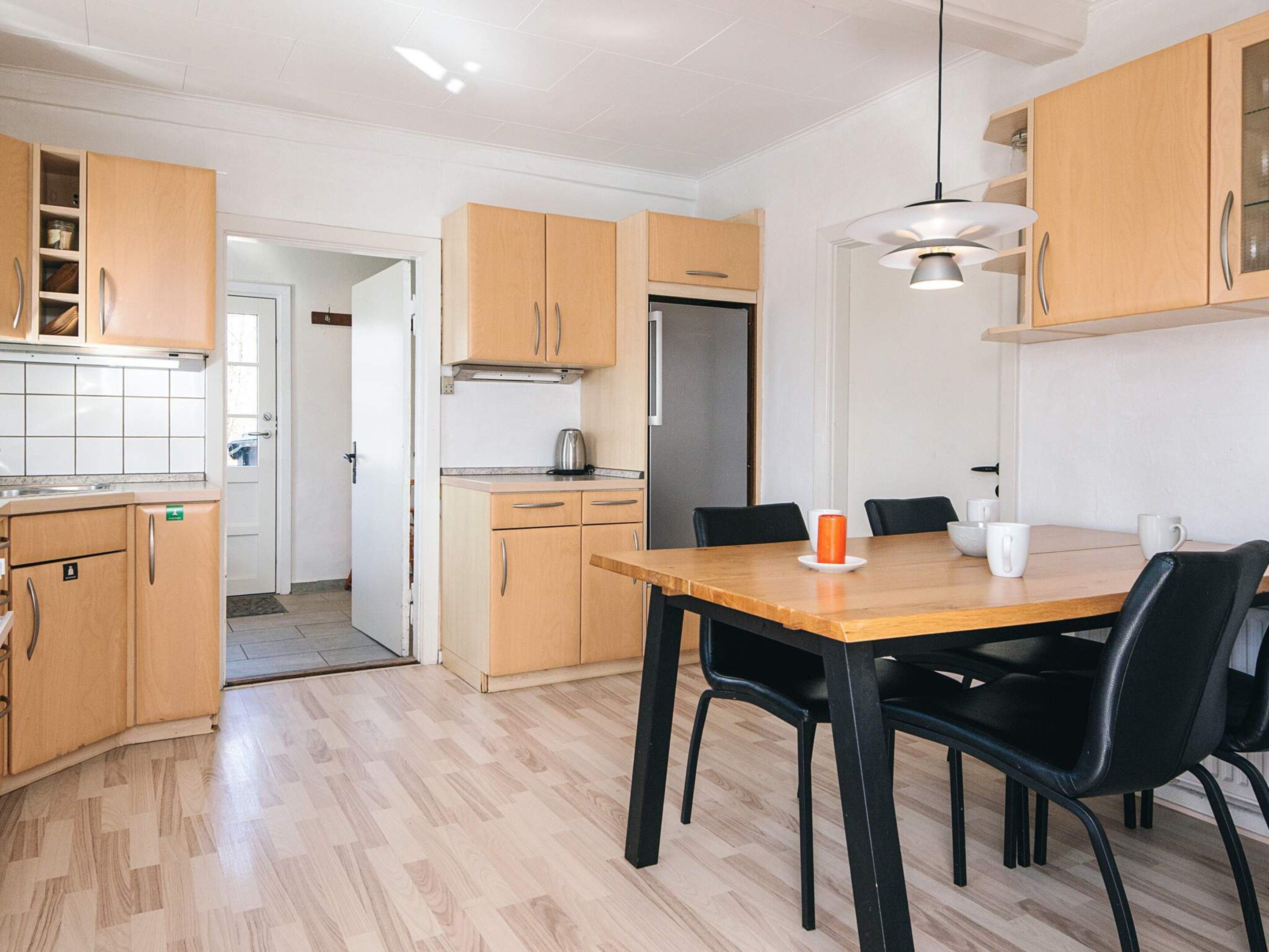 Une cuisine moderne avec des meubles en bois, une table à manger avec des chaises et un réfrigérateur.
