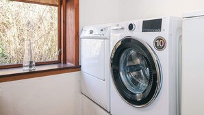 Eine Waschmaschine mit Frontlader und einem Aufkleber für eine 10-jährige Garantie, neben einem Fenster mit Holzrahmen.