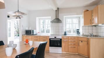 Una cocina moderna con armarios de madera, horno empotrado, microondas y un comedor con mesa y sillas.