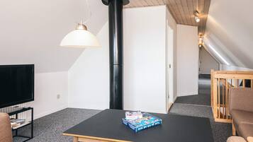 Una sala de estar moderna con una mesa negra, un televisor, un libro y una silla de madera.