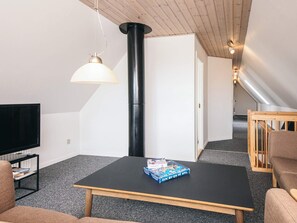 A modern living room with a black table, a television, a book, and a wooden chair.
