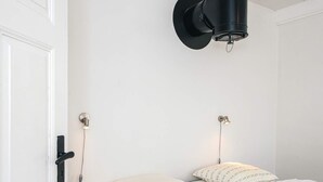 Ein Schlafzimmer mit einem Bett, zwei Wandlampen und einer Tür.