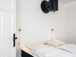 A bedroom with a bed, two wall-mounted lights, and a door.