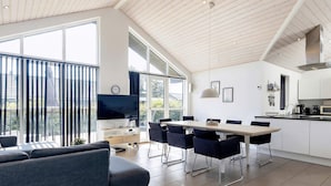 A modern living space with a dining area, a sofa, a TV, and a kitchen. - 8 Person Holiday Home in Hals-by Traum (Hals)