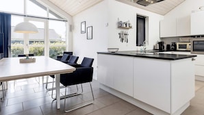 A modern kitchen with a large island, white cabinetry, and a dining area with a table and chairs. - 8 Person Holiday Home in Hals-by Traum (Hals)