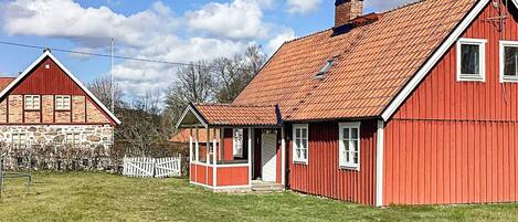 A red barn with a sloped roof and a small porch.
