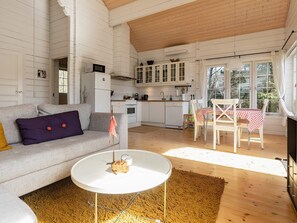 Ein gemütliches Wohnzimmer mit einer Couch, einem runden Couchtisch und einer Küchenzeile mit Schränken und einem Esstisch.