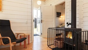 A cozy room with a black wood-burning stove, a wooden chair, and a small table. - 7 Person Holiday Home in Logstor (Logstor)