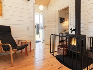A cozy room with a black wood-burning stove, a wooden chair, and a small table. - 7 Person Holiday Home in Logstor (Logstor)