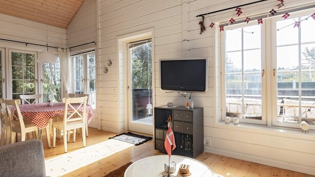 A cozy living room with a dining area, a flat-screen TV, and a view of the outdoors. - 7 Person Holiday Home in Logstor (Logstor)