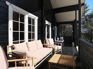 A wooden deck with a sofa, chairs, and a table.
