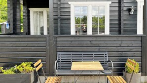 A wooden building with a porch, a bench, and two folding chairs. - 7 Person Holiday Home in Logstor (Logstor)