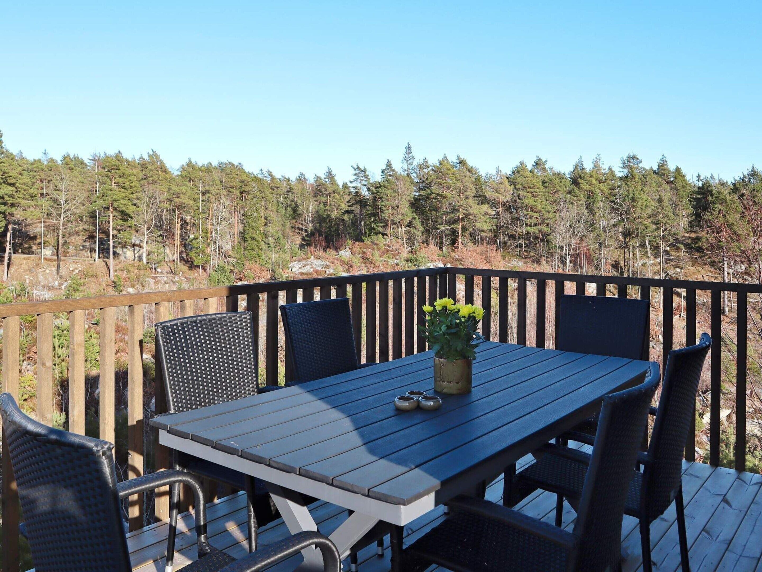 Une terrasse en bois avec une table et des chaises, donnant sur une zone boisée.