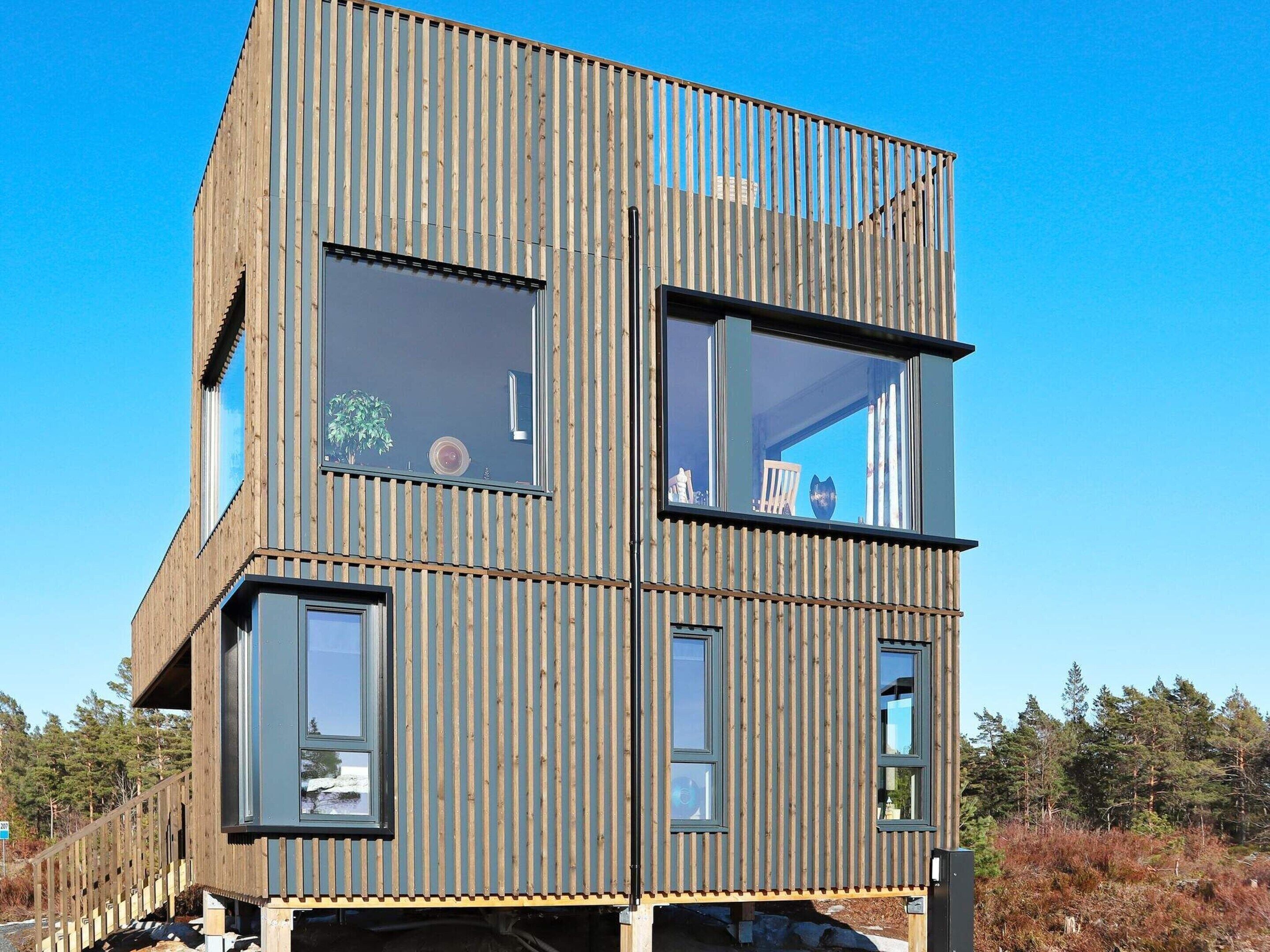 En moderne bygning med flere etager, store vinduer og en træfacade.