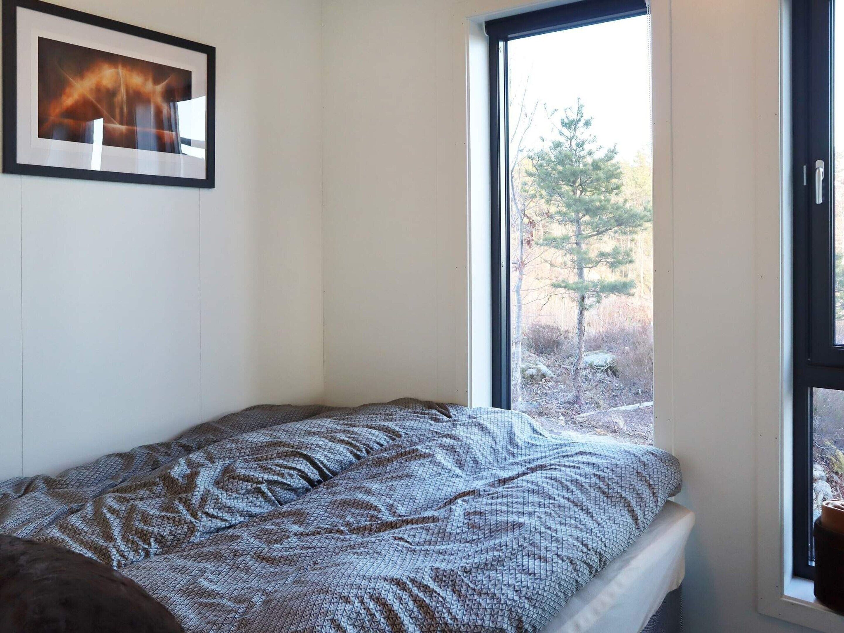 Un dormitorio pequeño con una cama individual, una ventana y un cuadro en la pared.