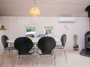 A dining area with a round table, six chairs, a hanging light fixture, and a fireplace. - 4 Person Holiday Home in Oksbol (Oksbol)