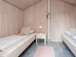 A room with two beds, a small white nightstand, a lamp, and a framed picture on the wall. - 4 Person Holiday Home in Oksbol (Oksbol)