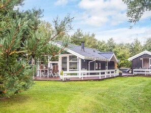 A cabin with a deck, a covered porch, and a chimney.