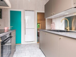 Una cocina moderna con una puerta color turquesa, electrodomésticos de acero inoxidable y un grifo dorado.