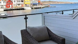 Un balcón con muebles de mimbre, vistas a edificios coloridos y una masa de agua tranquila.