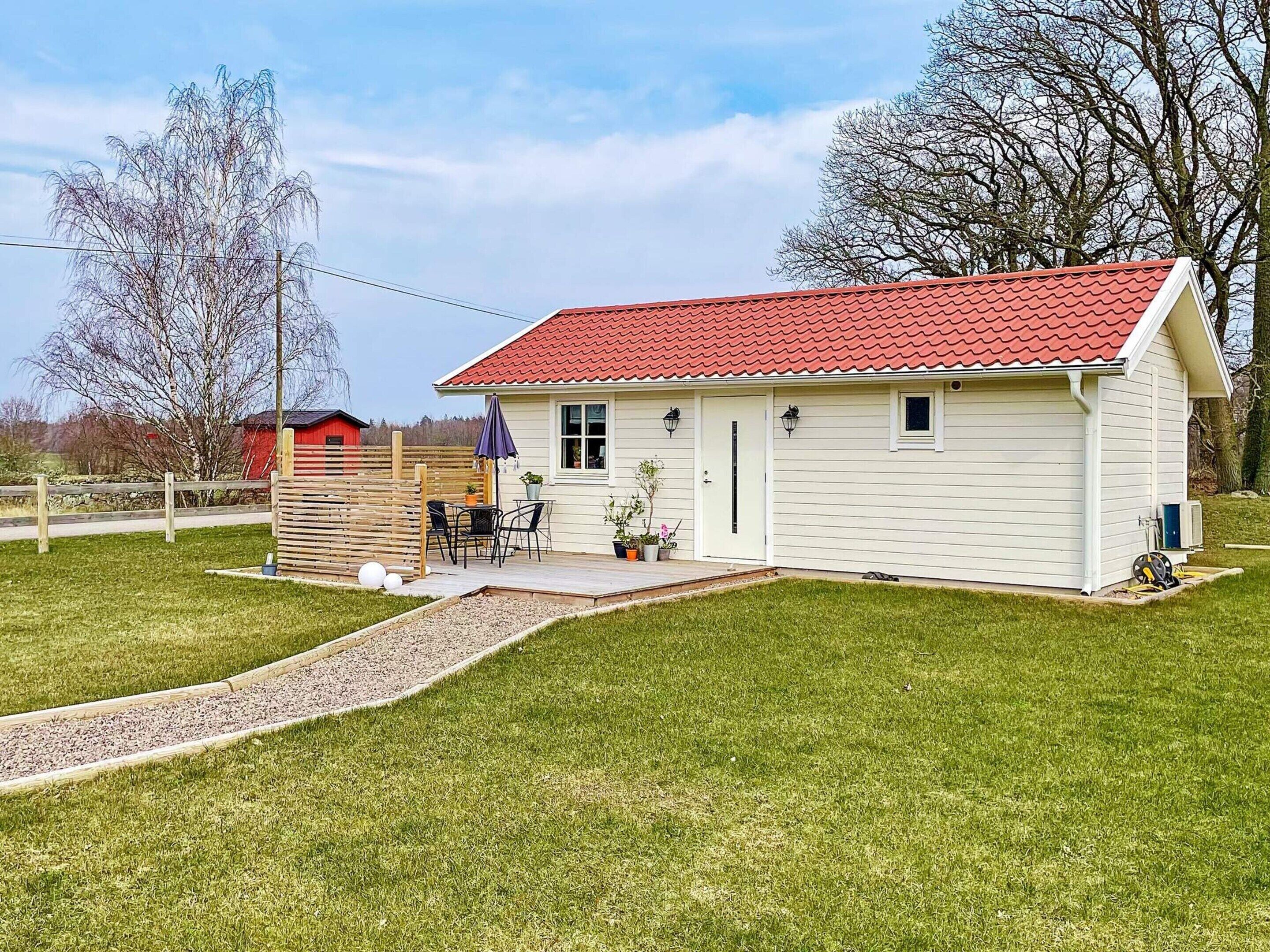 A single-story house with a red-tiled roof, a front porch, and a small patio area.